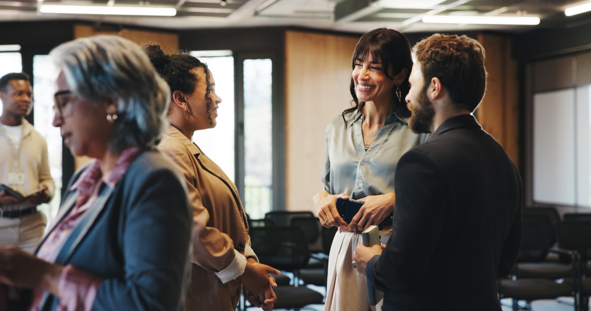 Membros conversando e sorrindo numa sala de evento de negócios